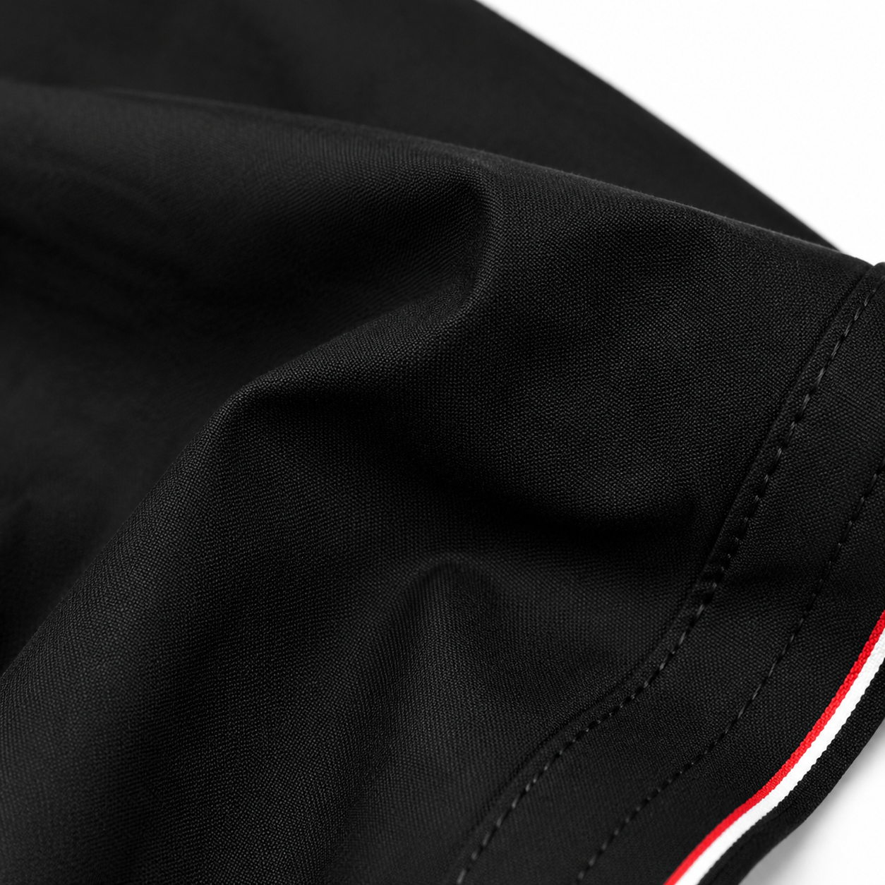 Close-up of black cotton fabric, tonal stitching and contrast piping